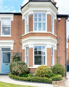 a large brick house with white trim and blue door