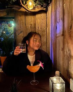 a woman sitting at a table with a drink in her hand