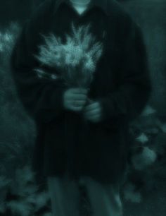 a man holding a bunch of white flowers in his hands and looking at the camera