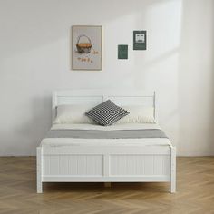 a white bed sitting on top of a hard wood floor next to a painting above it