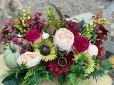 a vase filled with flowers sitting on top of a wooden table covered in greenery