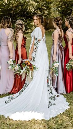 a group of women standing next to each other wearing dresses and holding bouquets in their hands