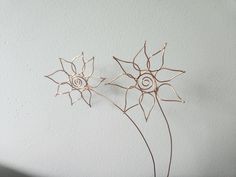 two metal flowers on a white wall