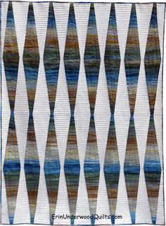 a quilted wall hanging with an abstract design in blue, brown and white colors