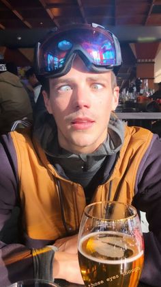 a man sitting at a table with a glass of beer in front of his face