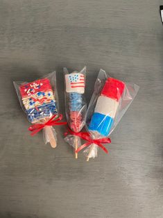 three lollipops wrapped in plastic and tied with red, white and blue ribbon