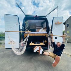 a man sitting in a hammock attached to the back of a van with his feet propped up