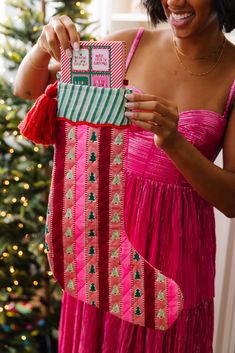 a woman in a pink dress holding up a christmas stocking