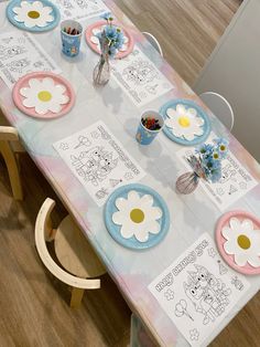 a table set up with plates and flowers on it for a child's birthday party