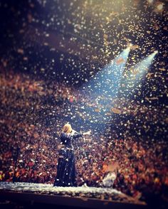 a woman standing on top of a stage in front of a crowd with confetti