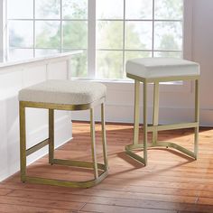 two stools sitting on top of a wooden floor in front of a white window