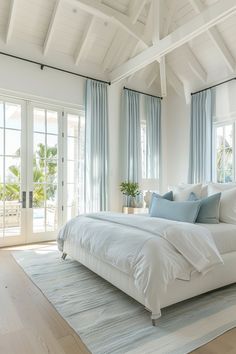 a large white bed sitting inside of a bedroom on top of a hard wood floor