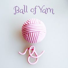 a pink ball of yarn sitting on top of a white table next to a pair of scissors