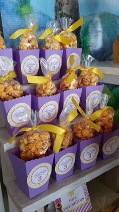 there are many bags of treats on the shelf together in purple boxes with yellow ribbons