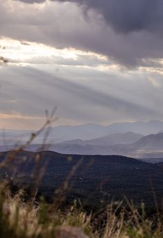 the sun is shining through the clouds over the hills and valleys in the distance, as seen from an overlook point