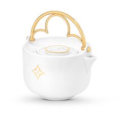 a white tea pot with gold handles and handle on the top, in front of a white background