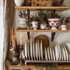 a shelf filled with dishes and plates next to a christmas wreath on top of a table