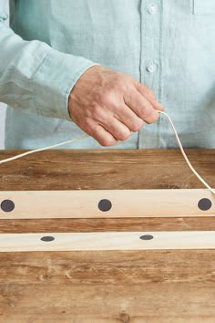 a person is stringing something on top of a wooden board with two holes in it