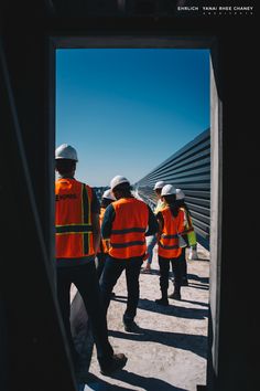 some construction workers are standing on the side of a building and looking at something in the distance