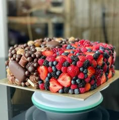 a cake covered in lots of different types of berries and chocolate on top of a plate