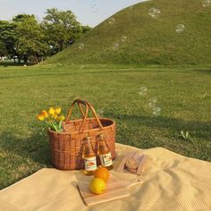 two bottles of beer sitting on top of a blanket next to a basket with lemons