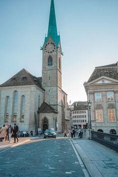 people are walking on the street in front of an old church