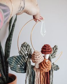 a person is holding up a small crochet mobile with leaves and beads on it