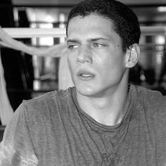 black and white photograph of a young man holding a cell phone to his ear while looking at the camera