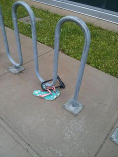 a pair of flip flops sitting on top of a sidewalk next to a bike rack