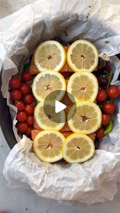 a bowl filled with lemons, tomatoes and cherries on top of white paper