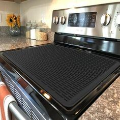 a stove top oven sitting inside of a kitchen next to a counter with flowers on it