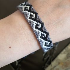 a close up of a person's arm wearing a bracelet with black and white beads