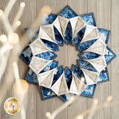 an ornament made out of blue and white paper on a wooden surface with lights in the background