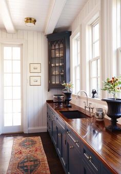 a kitchen with wooden floors and white walls, along with an area rug on the floor