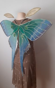 a dress made to look like a butterfly with wings on it's back, sitting on a mannequin