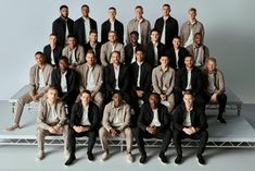 a group of men sitting next to each other in front of a white background with one man wearing a suit and tie