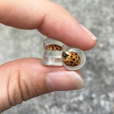 a person holding a tiny glass ring with a ladybug on it