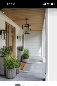 three large planters are on the front porch next to a door and light fixture