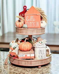 a three tiered tray with pumpkins and other decorations on top of a table