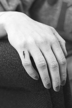 a woman's hand with a small lightning tattoo on it