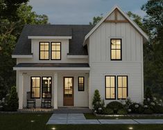 a white two story house with black shutters on the front and windows at night