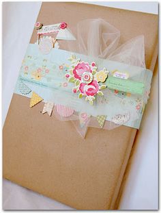 an open brown book with flowers and ribbons on the cover, sitting on a white surface