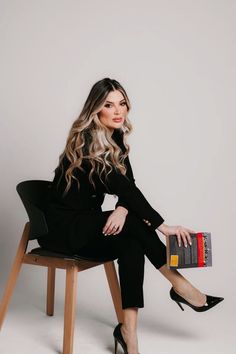 a woman sitting on top of a chair holding a book