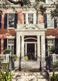 the front entrance to a large brick building with black wrought iron fence and gated entry