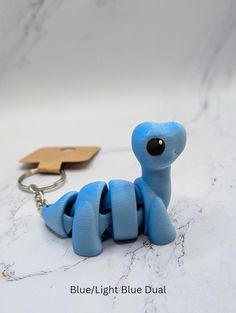 a blue toy sitting on top of a white counter next to a keychain