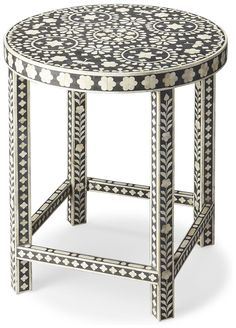 an ornately decorated side table with black and white dots on the top, sitting in front of a white background