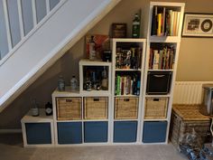 under the stairs is a bookshelf with baskets and other items