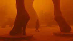 a person standing in front of two giant foot sculptures with fog covering the ground behind them