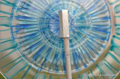 a blue and white glass plate with a metal object in the middle on it's side