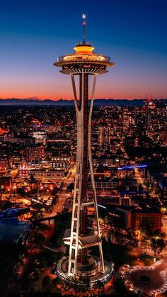 the space needle in seattle at night with lights on and buildings lit up behind it